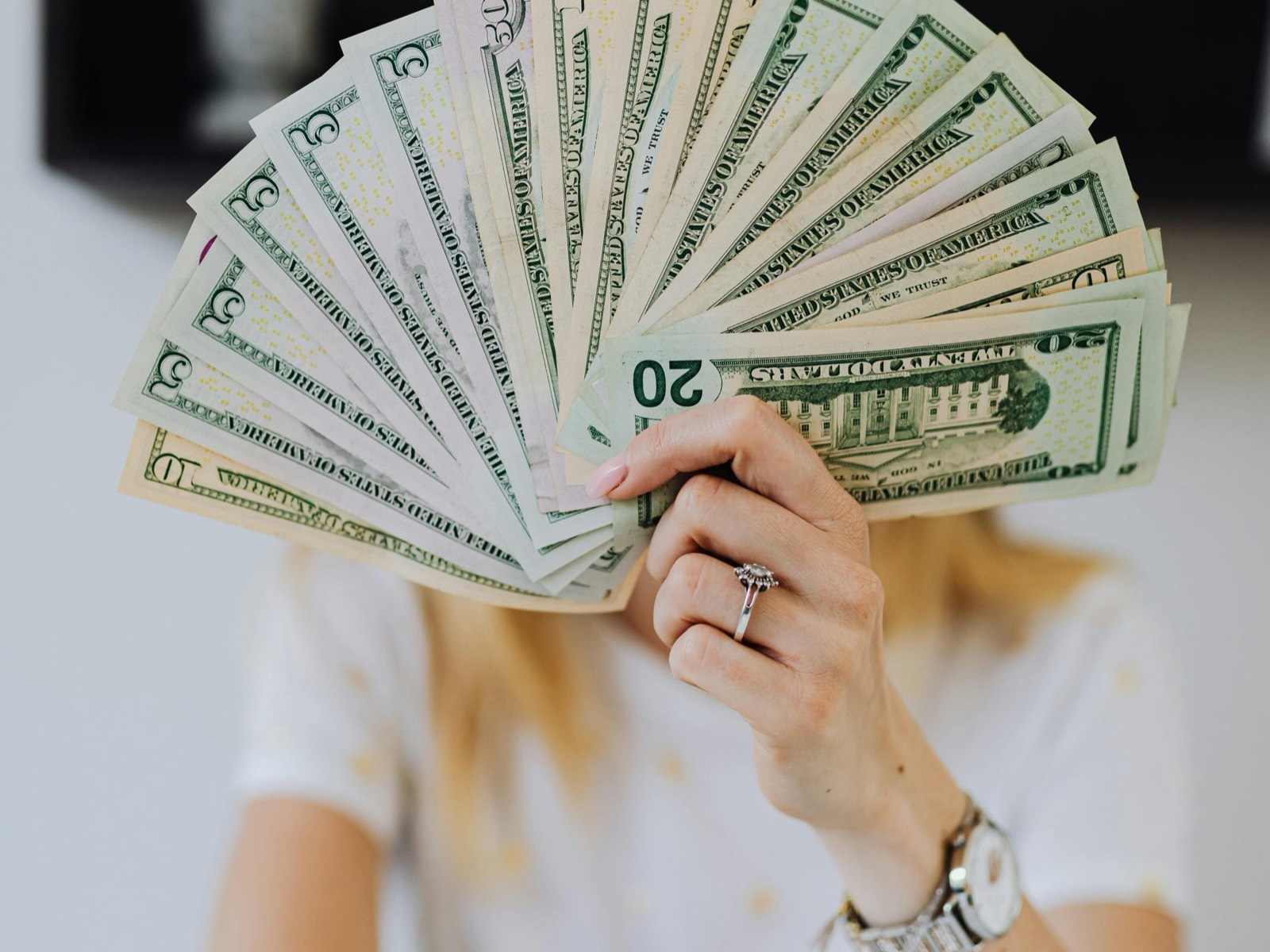 Person holding a fanned-out stack of US dollar bills
